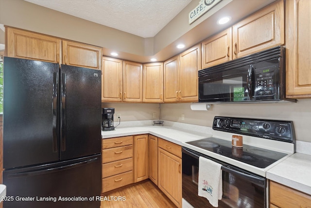 10949 Lakeside Dr, Perrinton, MI 48871 - kitchen featuring black appliances, light countertops, light wood-style floors, light brown cabinetry, and a textured ceiling