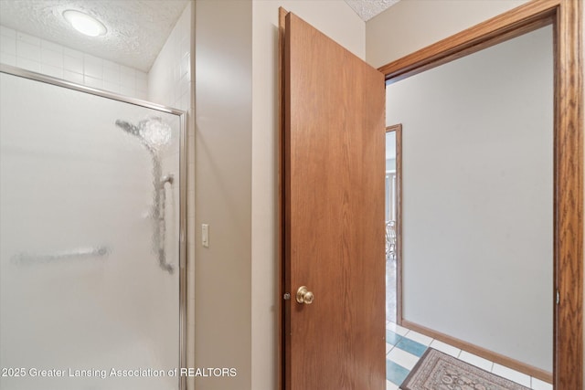 10949 Lakeside Dr, Perrinton, MI 48871 - bathroom featuring a textured ceiling, a stall shower, tile patterned floors, and baseboards