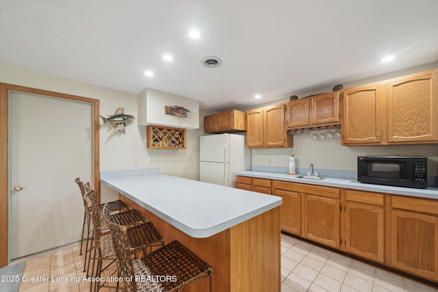 10949 Lakeside Dr, Perrinton, MI 48871 - kitchen featuring freestanding refrigerator, black microwave, a kitchen bar, light countertops, and a sink
