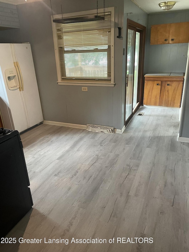 1846 Davis Ave, Lansing, MI 48910 - unfurnished dining area featuring light wood-style floors and wood walls