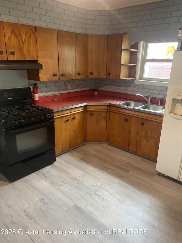 1846 Davis Ave, Lansing, MI 48910 - kitchen with black range with gas cooktop, white fridge with ice dispenser, light wood-style flooring, and brown cabinetry