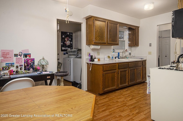 37936 Watkins Dr Unit 32, Sterling Heights, MI 48312 - kitchen with a sink, washing machine and dryer, light wood-type flooring, light countertops, and black microwave