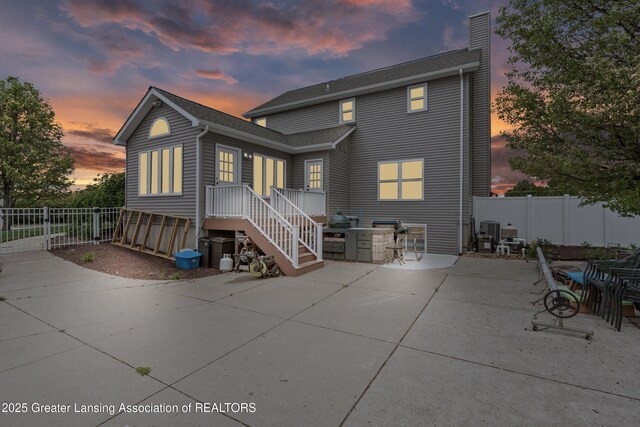1600 Tuttle Rd, Mason, MI 48854 - back of house at dusk with a chimney, a patio area, and central air condition unit