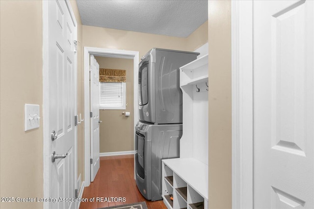 703 Hastay Blvd, Eaton Rapids, MI 48827 - laundry area featuring stacked washer / dryer, dark wood-type flooring, baseboards, and a textured ceiling