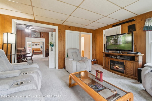6275 E Clark Rd, Bath, MI 48808 - living room featuring wooden walls, carpet flooring, a ceiling fan, a drop ceiling, and a glass covered fireplace