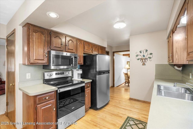 14921 Karl Dr, Lansing, MI 48906 - kitchen featuring appliances with stainless steel finishes, a sink, light countertops, light wood-type flooring, and baseboards
