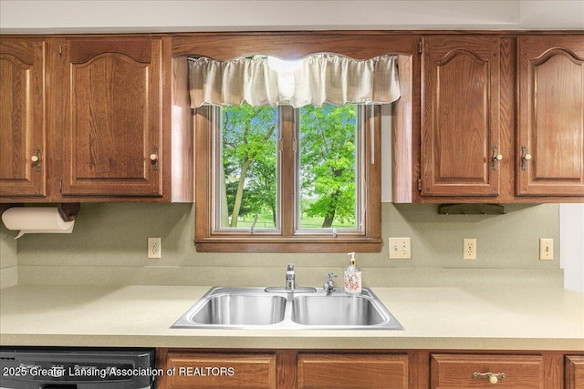 14921 Karl Dr, Lansing, MI 48906 - kitchen featuring dishwashing machine, a sink, light countertops, and brown cabinetry