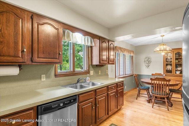 14921 Karl Dr, Lansing, MI 48906 - kitchen featuring stainless steel dishwasher, a sink, hanging light fixtures, light countertops, and light wood finished floors