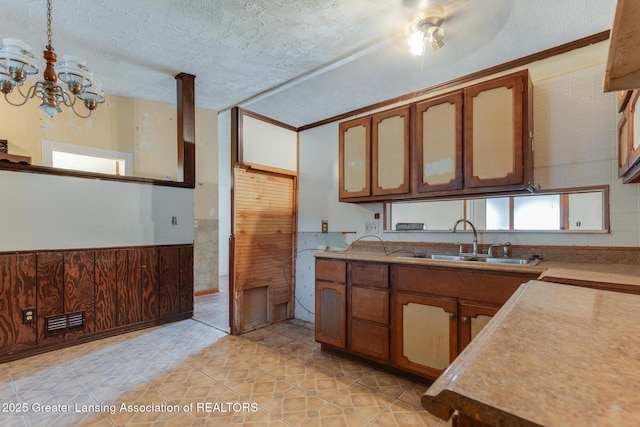 4316 Dumfries Cir, Lansing, MI 48911 - kitchen featuring a sink, brown cabinets, a chandelier, wainscoting, and light countertops