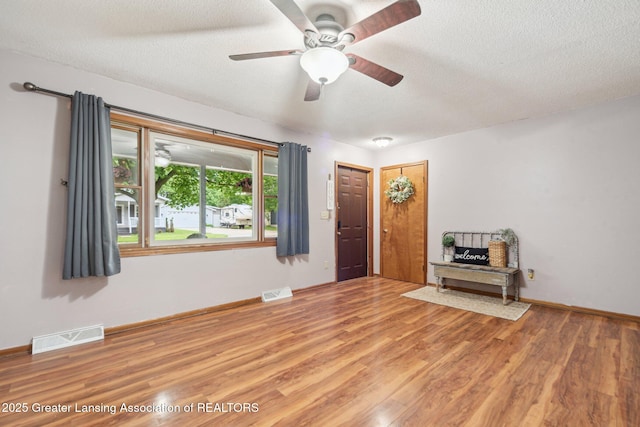 445 S Oak St, Maple Rapids, MI 48853 - unfurnished living room featuring light wood finished floors, a textured ceiling, a ceiling fan, and baseboards