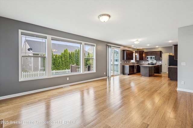 619 Willet Way E, Lansing, MI 48823 - unfurnished living room with light wood-style flooring, baseboards, and recessed lighting