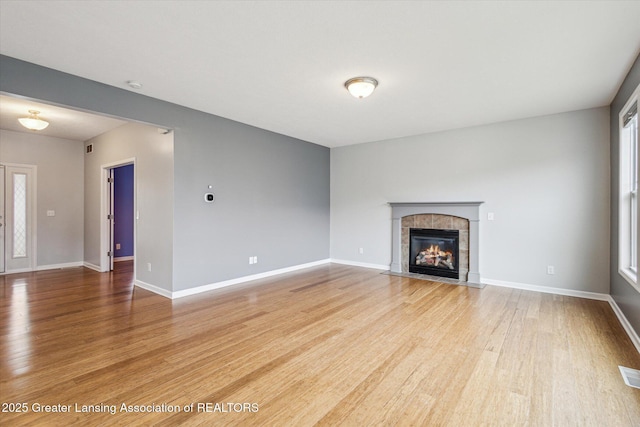 619 Willet Way E, Lansing, MI 48823 - unfurnished living room with wood finished floors, a tile fireplace, and baseboards