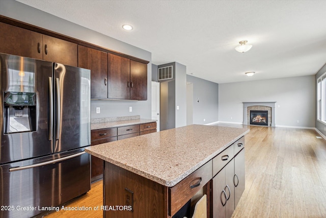 619 Willet Way E, Lansing, MI 48823 - kitchen featuring stainless steel fridge, light wood-type flooring, a kitchen island, light stone counters, and dark brown cabinetry