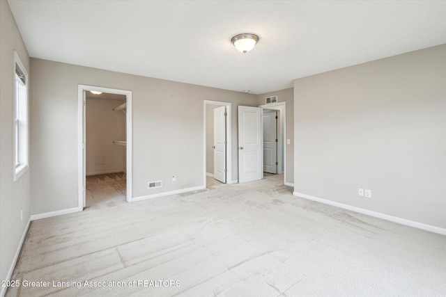 619 Willet Way E, Lansing, MI 48823 - unfurnished bedroom featuring light colored carpet, baseboards, a walk in closet, and a closet