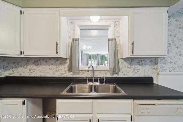 139 W Mansion St, Jackson, MI 49203 - kitchen with wallpapered walls, dishwasher, a sink, dark countertops, and white cabinets