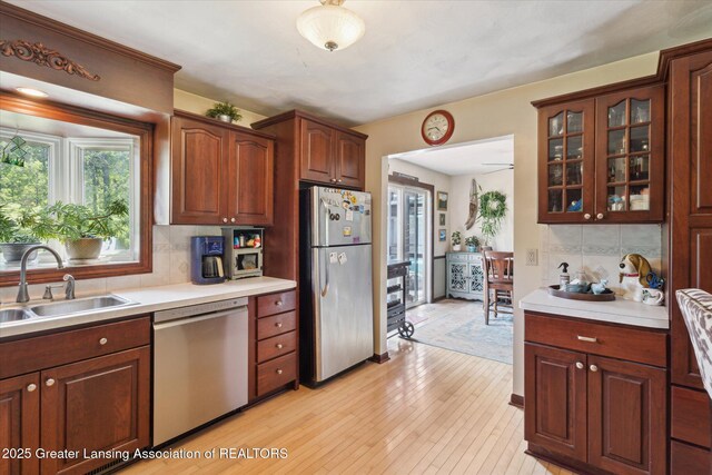7050 E Eaton Hwy, Sunfield, MI 48890 - kitchen with appliances with stainless steel finishes, a sink, decorative backsplash, light countertops, and glass insert cabinets