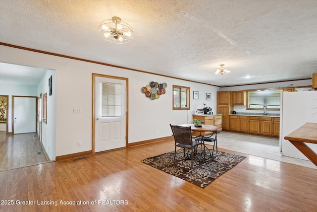7161 E Eaton Hwy, Mulliken, MI 48861 - dining space featuring a chandelier, light wood-type flooring, crown molding, a textured ceiling, and baseboards