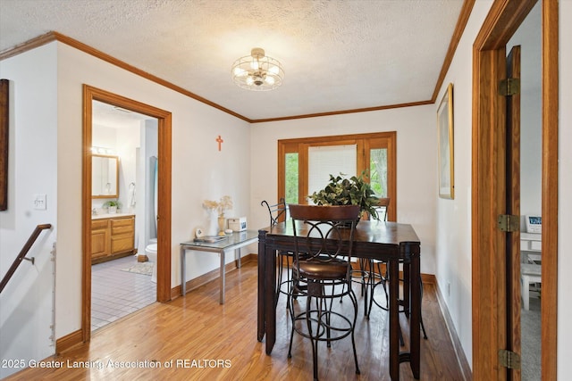 7161 E Eaton Hwy, Mulliken, MI 48861 - dining room featuring light wood-type flooring, a chandelier, a textured ceiling, baseboards, and ornamental molding