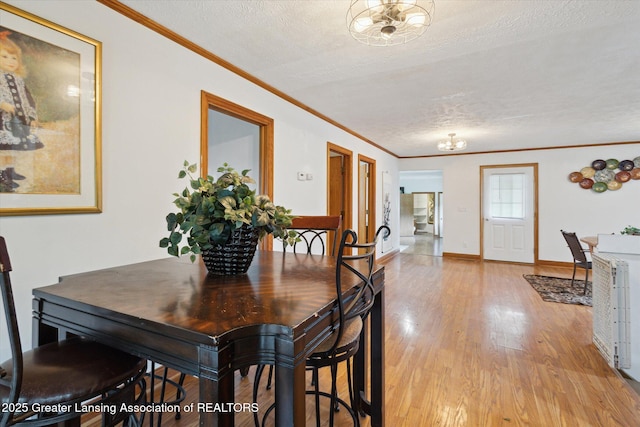7161 E Eaton Hwy, Mulliken, MI 48861 - dining space featuring light wood-style flooring, crown molding, a textured ceiling, and baseboards