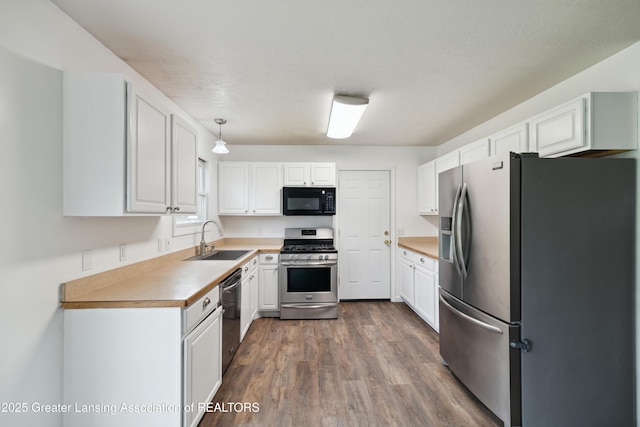 114 Walker Dr, Morrice, MI 48857 - kitchen with appliances with stainless steel finishes, a sink, white cabinets, and dark wood-type flooring