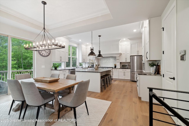 16851 Meadowbrook Dr, Haslett, MI 48840 - dining room featuring a chandelier, light wood-style floors, recessed lighting, ornamental molding, and a tray ceiling