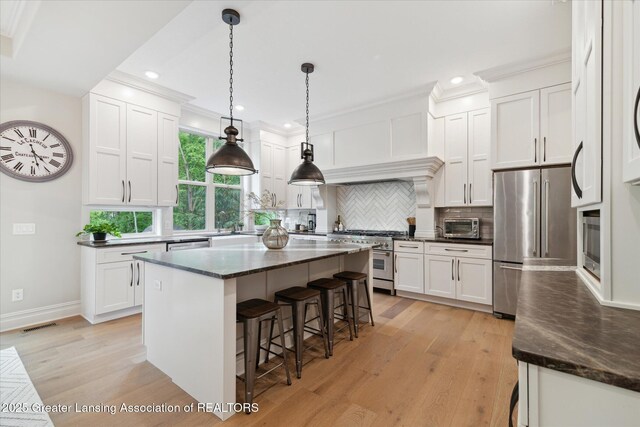 16851 Meadowbrook Dr, Haslett, MI 48840 - kitchen with high end appliances, light wood-style floors, a kitchen breakfast bar, white cabinetry, and recessed lighting