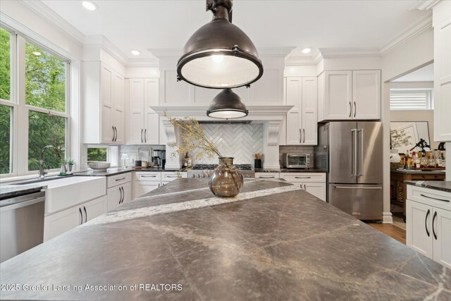 16851 Meadowbrook Dr, Haslett, MI 48840 - kitchen featuring appliances with stainless steel finishes, white cabinetry, tasteful backsplash, pendant lighting, and ornamental molding