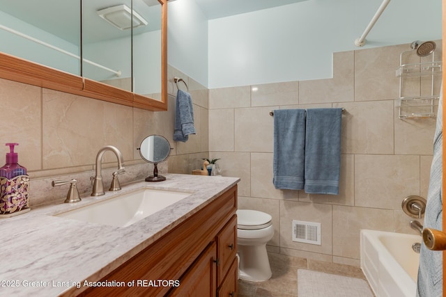 15157 Chetwyn Dr, Lansing, MI 48906 - full bathroom featuring tile walls, toilet, vanity, bathing tub / shower combination, and tile patterned flooring
