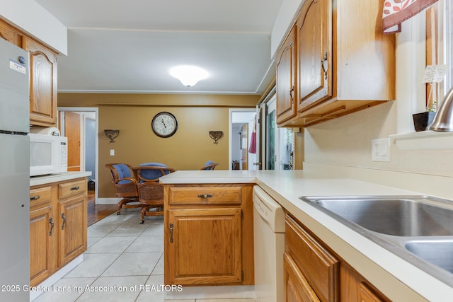 15157 Chetwyn Dr, Lansing, MI 48906 - kitchen featuring white appliances, a peninsula, light countertops, light tile patterned floors, and brown cabinets