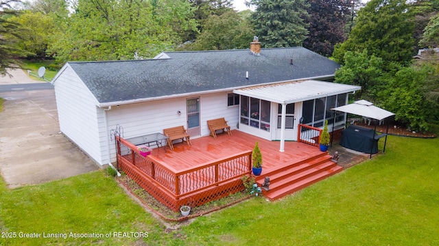 15157 Chetwyn Dr, Lansing, MI 48906 - rear view of house with a sunroom, a shingled roof, a chimney, a deck, and a lawn