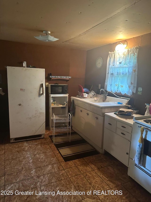 1364 James St, Harrison, MI 48625 - kitchen with white cabinets, stove, black microwave, and light countertops