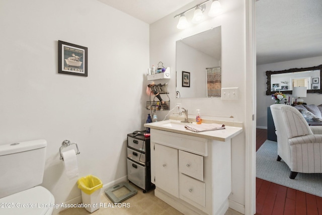 620 Irvington Ave, Lansing, MI 48910 - ensuite bathroom featuring vanity, toilet, wood finished floors, and baseboards