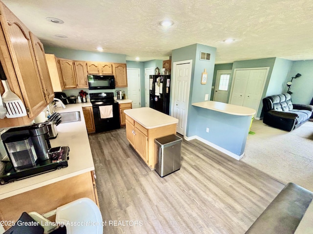 405 N Iris Ln, Laingsburg, MI 48848 - kitchen featuring black appliances, light wood-style flooring, light countertops, a center island, and a textured ceiling
