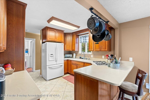 218 Russell St, Grand Ledge, MI 48837 - kitchen with white appliances, a sink, a peninsula, light countertops, and a textured ceiling