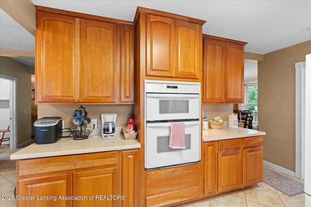 218 Russell St, Grand Ledge, MI 48837 - kitchen featuring white double oven, light countertops, and brown cabinetry