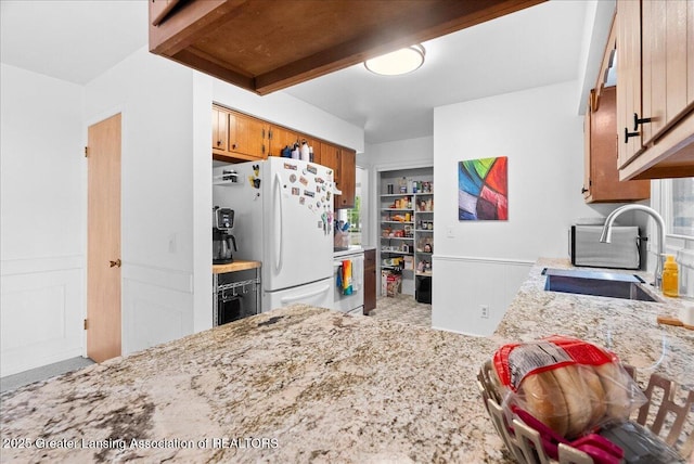 420 John R St, East Lansing, MI 48823 - kitchen featuring a sink, white appliances, brown cabinets, light stone counters, and carpet