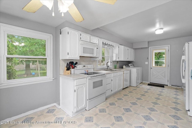 407 Kearney St, Portland, MI 48875 - kitchen featuring white appliances, light countertops, a sink, white cabinetry, and separate washer and dryer