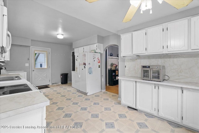 407 Kearney St, Portland, MI 48875 - kitchen with white appliances, arched walkways, white cabinetry, light countertops, and ceiling fan