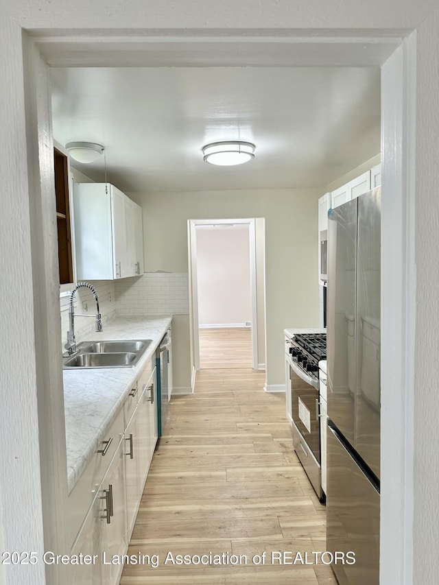 218 S Hayford Ave, Lansing, MI 48912 - kitchen with stainless steel appliances, a sink, tasteful backsplash, white cabinets, and light wood finished floors