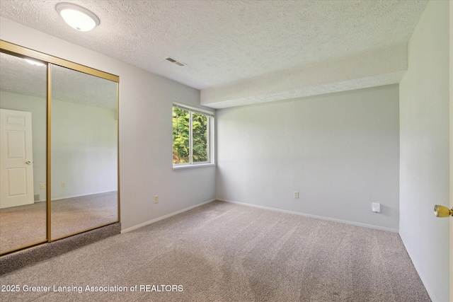 820 Kenwood Ave, Lansing, MI 48910 - unfurnished bedroom featuring a textured ceiling, carpet, a closet, and baseboards