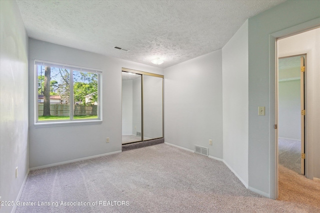 820 Kenwood Ave, Lansing, MI 48910 - unfurnished bedroom with carpet flooring, a textured ceiling, a closet, and baseboards