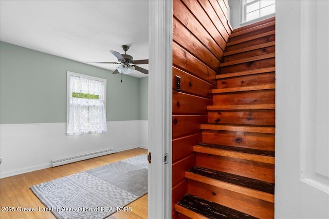 1218 Woodbine Ave, Lansing, MI 48910 - stairway featuring baseboard heating, plenty of natural light, ceiling fan, and wood finished floors