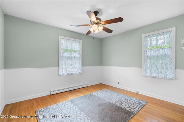 1218 Woodbine Ave, Lansing, MI 48910 - spare room featuring a baseboard radiator, healthy amount of natural light, a ceiling fan, and wood finished floors