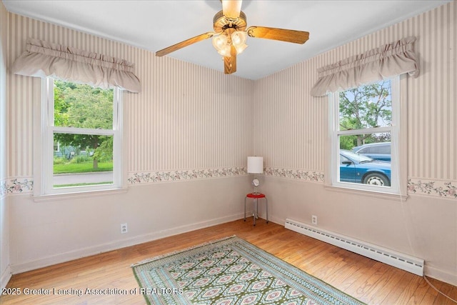 1218 Woodbine Ave, Lansing, MI 48910 - empty room featuring a baseboard heating unit, light wood finished floors, baseboards, wallpapered walls, and ceiling fan