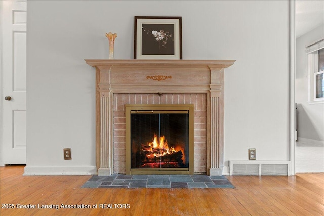 1218 Woodbine Ave, Lansing, MI 48910 - detailed view of wood finished floors, a brick fireplace, and baseboards