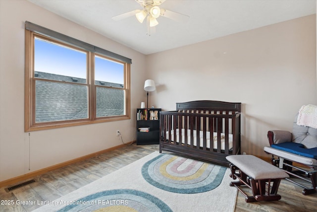549 Riverwalk Dr, Mason, MI 48854 - bedroom featuring wood finished floors, baseboards, a ceiling fan, and a crib
