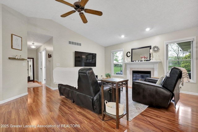 722 Fieldview Dr, Grand Ledge, MI 48837 - living area with wood finished floors, plenty of natural light, a tile fireplace, ceiling fan, and lofted ceiling