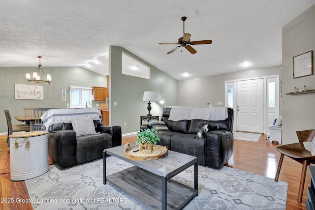 722 Fieldview Dr, Grand Ledge, MI 48837 - living room with lofted ceiling, light wood-style flooring, a ceiling fan, a chandelier, and a textured ceiling