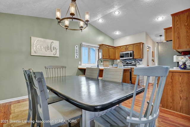 722 Fieldview Dr, Grand Ledge, MI 48837 - dining space featuring a textured ceiling, a chandelier, light wood-style flooring, vaulted ceiling, and baseboards