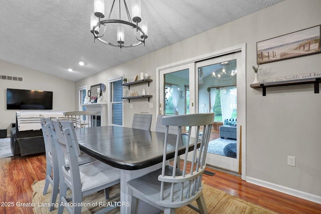722 Fieldview Dr, Grand Ledge, MI 48837 - dining area with wood finished floors, a chandelier, a textured ceiling, lofted ceiling, and baseboards